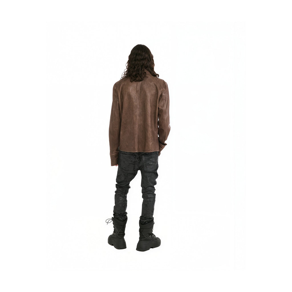 A model shown from the back wearing a brown leather jacket, dark gray jeans, and black boots against a solid white background.