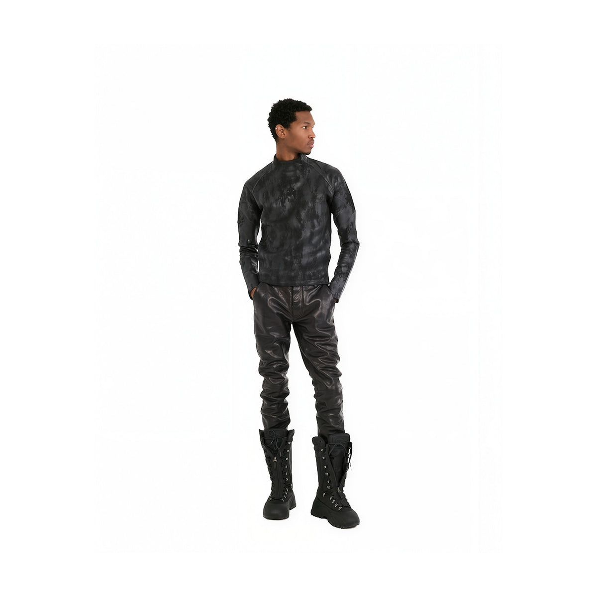 A man modeling a black textured leather or faux-leather long-sleeve top and matching pants with black lace-up boots, shown against a plain white background.